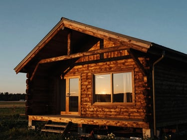 Dramatic architectural wide shot of a luxury wooden cabin at twilight, warm golden-hour side-lighting, deep rich wood tones, medium format film look