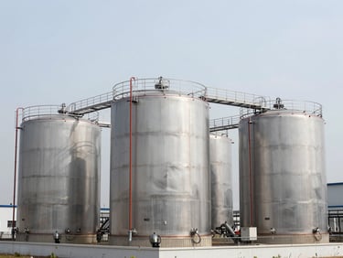 Modern chemical storage facility with pristine stainless steel tanks, clean industrial architecture, bright cool daylight