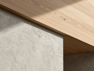 Tight abstract detail crop of raw concrete meeting warm oak wood, soft diffused light, minimalist architectural texture