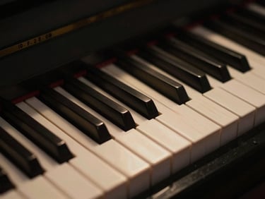 Close-up of analog music gear, piano keys in deep shadow with a soft golden glow catching the wood grain, low-key lighting