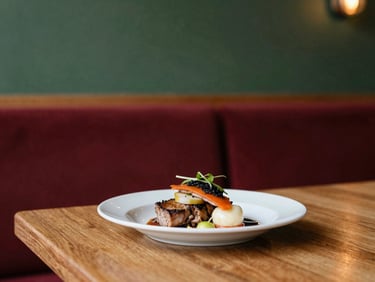 Cozy Scandinavian-style restaurant interior, warm ambient light, a beautifully plated dish on a wooden table, shallow depth of field.