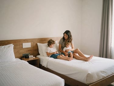 A clean, functional family hotel room with three beds, warm gentle Mediterranean sun, soft desaturated tones, authentic family moment, 35mm film look.