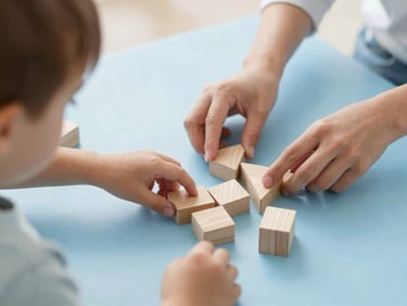 A child playing with wooden geometric blocks on a light blue mat, hands of a therapist guiding gently, warm natural light.