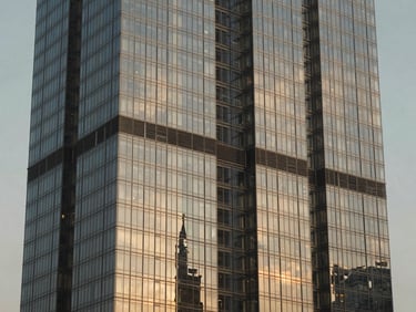 High-contrast architectural detail of a modern glass skyscraper in Dubai, warm late-afternoon sun reflection, sophisticated tones.