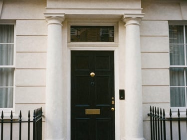 Warm editorial photography of a classic London townhouse entrance, white stucco column, soft natural light, architectural focus, medium format film.