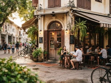 Warm, inviting exterior shot of CAFETERIA CORNER on Jalan Sepoy Lines, showing the entrance and outdoor seating, soft morning light, rich cream and coffee tones, shallow depth of field.