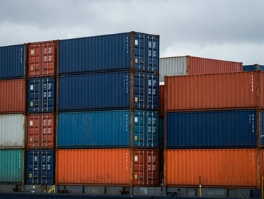 Dramatic overcast maritime daylight, close-up of industrial shipping containers stacked high on a vessel deck, cool high-contrast tones