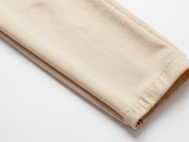Overhead flat-lay close-up of a folded Barbie-fabric trouser swatch on a plain white surface, even studio lighting, showing smooth face finish and tight uniform weave, no human subject, no background clutter