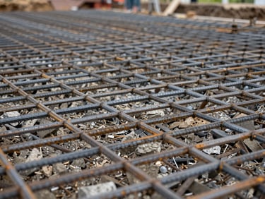 Close detail shot of rebar grid laid in a residential foundation excavation, aggregate base visible beneath, overcast natural daylight, no people, ground-level framing