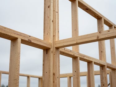 Close-up documentary shot of ADU framing joints and wall studs mid-build, natural overcast daylight filtering through open framing, raw lumber texture visible, no people