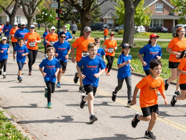 Families and kids running together in a local charity fun run, energetic crowd, sunny Ohio park