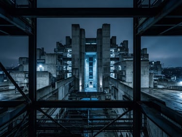 Wide panoramic shot of a brutalist concrete structure, sharp shadows, low-key blue lighting, symmetrical composition, structural steel beams in the foreground.