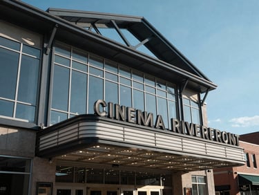 Crisp daytime exterior of the Penn Cinema Riverfront theater, highlighting modern steel framing and glass panels against a clear blue sky