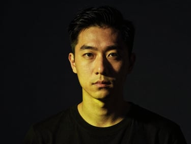 High-contrast studio portrait of a creator looking intensely at the camera, dramatic shadows, hard key lighting.