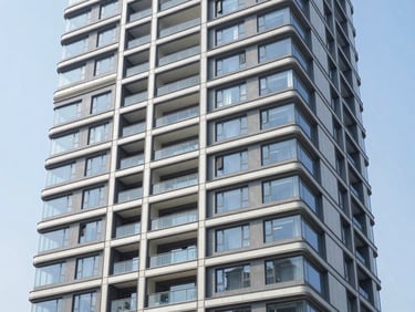 Wide architectural shot of a modern residential tower with clean geometric lines, bright natural daylight, 35mm lens