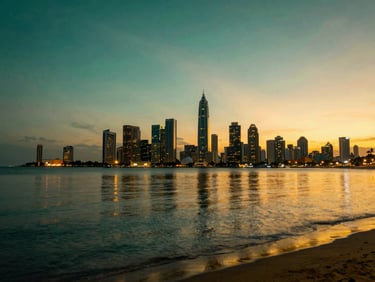 Wide panoramic view of Colombo Port City at dusk, golden lights reflecting on calm ocean water.