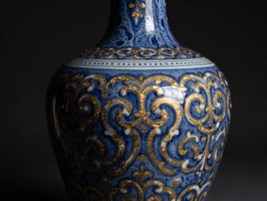 A hand-turned blue ceramic vase with intricate hand-painted patterns, glossy glaze catching warm highlights against a dark background.