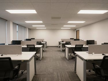 Straight-on photograph of a clean open-plan commercial office with wiped desks, vacuumed carpet, and even overhead lighting, empty of staff, finished state clearly shown
