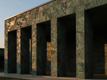 Low-key architectural photograph of a modern pavilion facade clad in textured green Kota stone, dramatic side lighting from the setting sun, 35mm