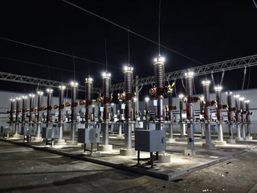 Wide shot of a modern high-voltage electrical substation, cool metallic lighting, sharp high-contrast dark tones, technical precision, wide-angle lens