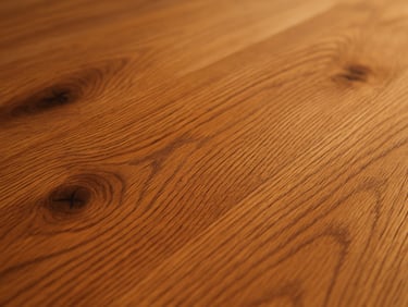 Extreme close-up of solid hardwood plank surface in warm oak, visible grain lines and natural knots under soft daylight, slight sheen on the finished face, photographed at a low angle to emphasize depth
