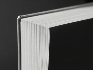 Macro close-up of a heavy textured paper book spine, deep shadows, natural side light, monochrome ink tones