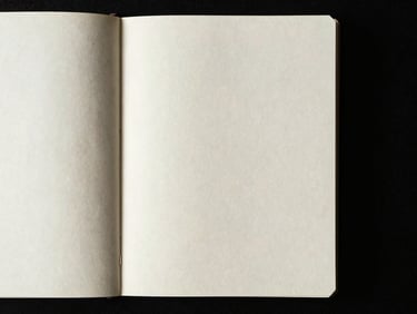 Close-up of open blank pages of a minimalist notebook, high-contrast side lighting, deep shadows, 35mm grain