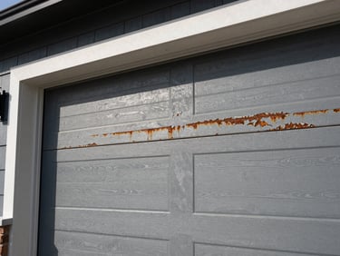Close-up of a worn residential garage door roller, showing rust or damage. Overhead garage lighting, sharp details.