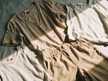 Flat-lay of a curated weekend outfit with breathable fabrics, soft shadows, warm diffused natural daylight, muted earth tones, 35mm film aesthetic