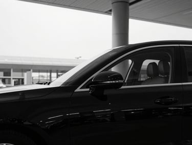 Close-up of a pristine black sedan parked at a modern airport terminal under overcast daylight