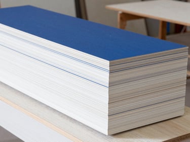 Stacked premium Swedish wood and MDF sheets in a clean, well-lit architectural workshop, bright daylight.