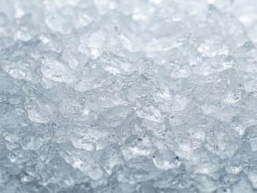 Macro photograph of clean, dense flake ice glistening under cool clinical light, sharp focus on ice textures, 35mm