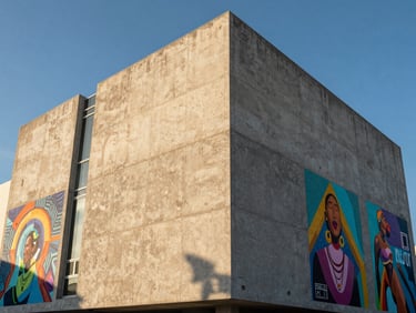 Low angle shot of a modern concrete facade in Wynwood with vibrant public art installations, crisp afternoon light