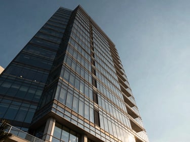 Dramatic low-angle looking up at a glass skyscraper in Brickell, coastal sunlight reflecting off the facade