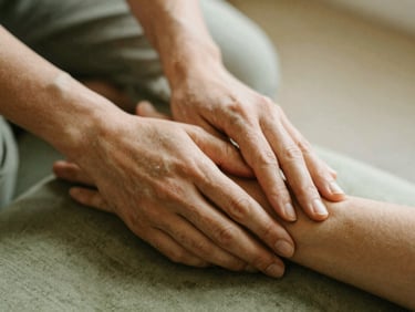 Close-up of hands gently placed on a forearm, illustrating therapeutic touch, warm diffused light, natural textures, shallow depth of field.