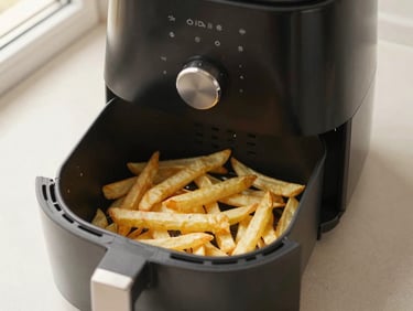 Overhead shot of a modern black air fryer, cooking hand-cut fries, natural kitchen daylight, warm neutral tones, crisp detail.