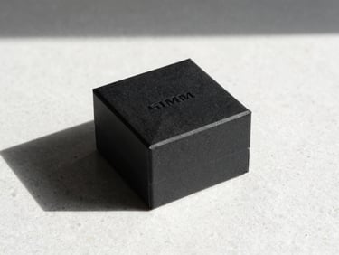 Minimalist layout of premium black jewelry gift box on a white textured stone surface, sharp direct sunlight, high contrast, 35mm