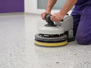 Close-up of a professional floor technician operating a heavy-duty rotary polishing machine on a high-gloss terrazzo floor.