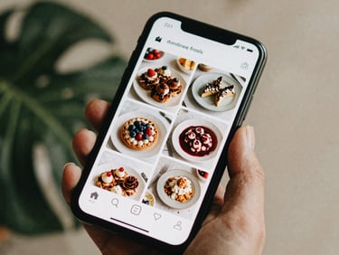 Overhead shot of a smartphone displaying a beautifully curated social media feed with artisanal food photos, soft natural daylight, scandinavian style.