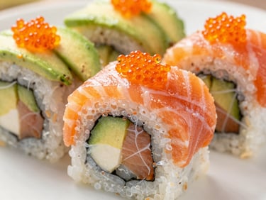 Macro shot of Spicy Salmon Roll with orange tobiko and fresh avocado slice, bright daylight, shallow depth of field