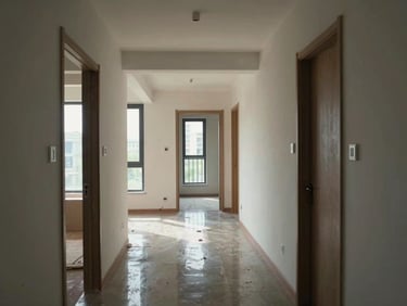 Interior corridor of a completed residential building with natural window light, polished floor reflecting ambient light, doors to individual units visible, showing occupied and finished common areas