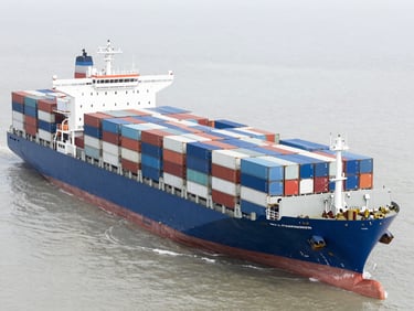 Overhead shot of a container ship being loaded at a large, organized port, bright neutral daylight, cool slate and blue tones, sharp focus, editorial style.