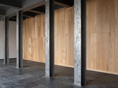 Modern commercial studio interior featuring raw steel columns, dark slate flooring, and textured acoustic wood panels, crisp architectural focus