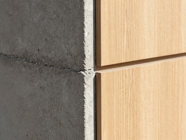 Close-up of architectural material joints, raw concrete meeting smooth oak paneling, crisp directional daylight, sharp focus