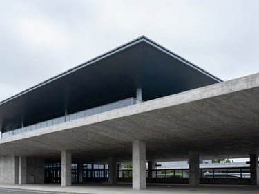 Crisp architectural photography of a completed concrete municipal transit hub with clean geometric lines under cool overcast skies