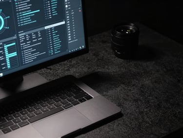 Close-up of a sleek, minimalist desk setup with a high-resolution monitor displaying secure network graphs, brushed metal laptop, and dark stone surface, moody low-key lighting, deep shadows, cool dark tones, high-contrast, 35mm lens