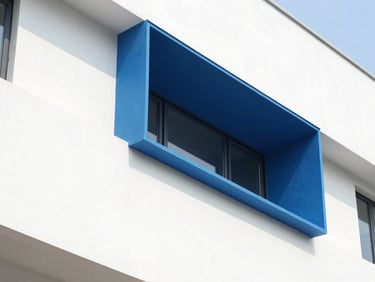 Vivid architectural detail of a modern building exterior, bright daylight casting sharp geometric shadows on a clean white wall with a bold electric blue painted accent, sharp focus.