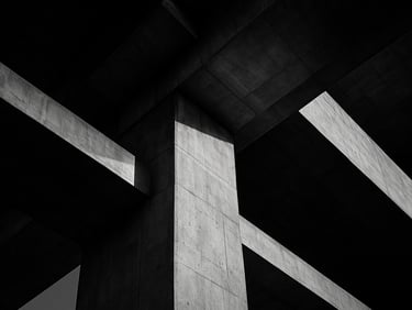 Extreme close-up of a massive concrete bridge pier junction, sharp shadow play, dramatic late-afternoon light, technical structural precision.