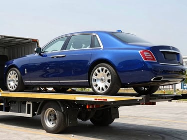 A luxury sedan being loaded onto a specialized closed car carrier with hydraulic ramps