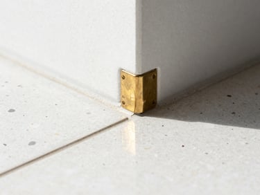 Macro architectural photography of a pristine raw brass joint meeting polished terrazzo, bright natural daylight, clean reflections